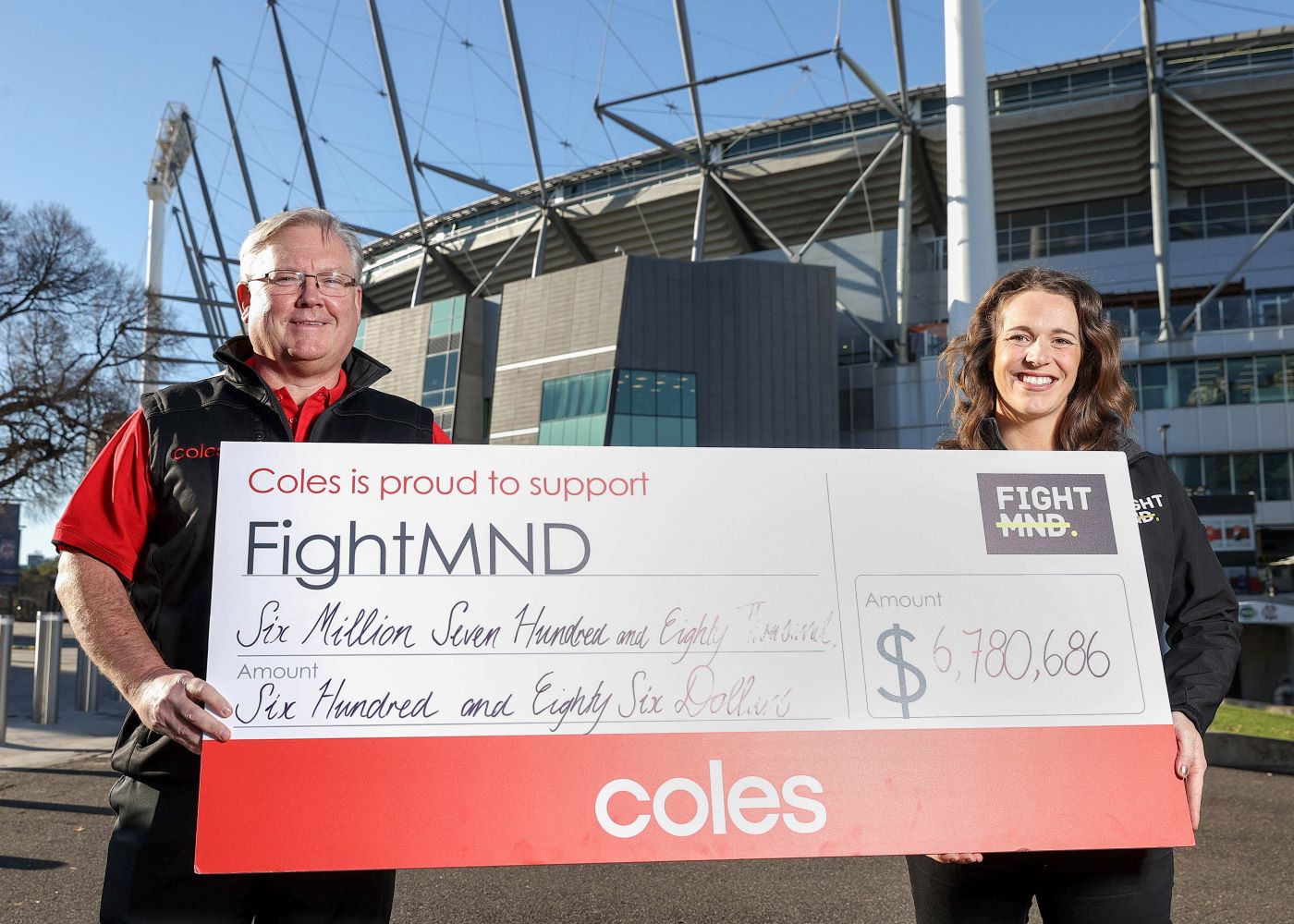 Coles Group CEO Steven Cain presents a cheque of $6.7m to FightMND Campaign Director Bec Daniher 
