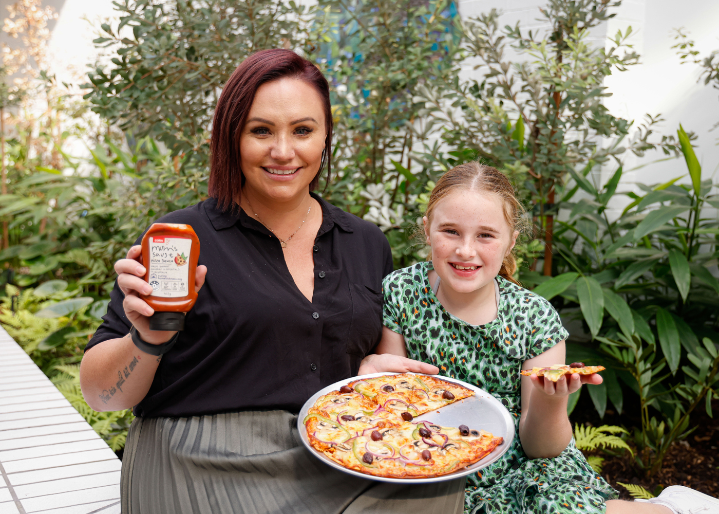 Nine year-old Indy who has Partial Complex Cognitive Epilepsy with her mum holding a bottle of Mum's Sause